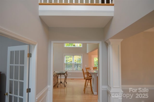 hall with ornate columns and light wood-type flooring