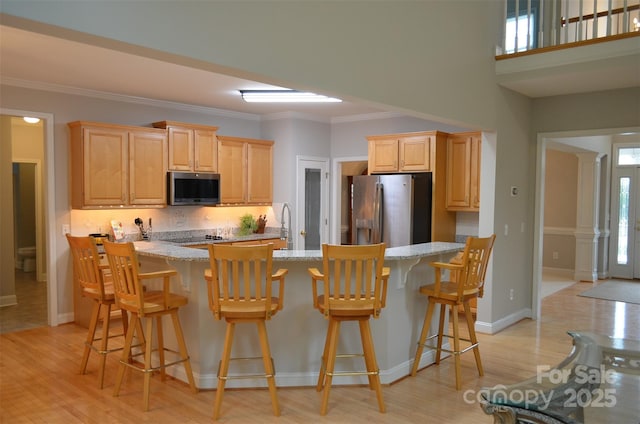 kitchen featuring light brown cabinets, light stone counters, ornamental molding, and stainless steel appliances