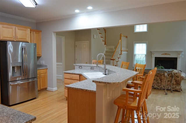 kitchen featuring sink, light brown cabinets, stainless steel fridge with ice dispenser, a breakfast bar area, and a kitchen island with sink