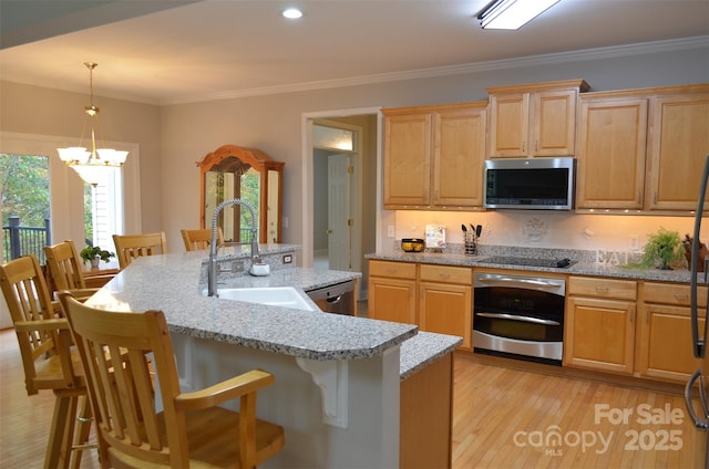 kitchen featuring a breakfast bar, stainless steel appliances, sink, a chandelier, and an island with sink