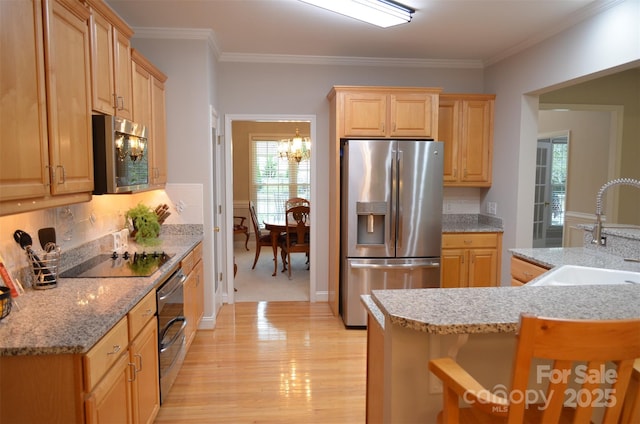 kitchen with a kitchen bar, appliances with stainless steel finishes, ornamental molding, sink, and an inviting chandelier