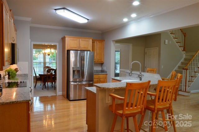 kitchen featuring a breakfast bar, stainless steel fridge, sink, and ornamental molding