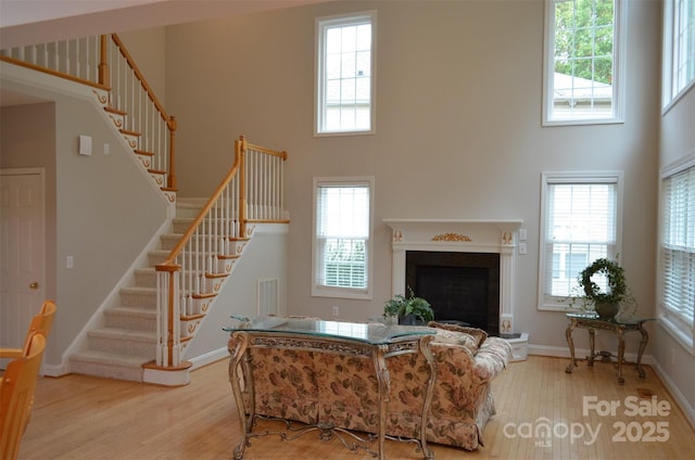 living room with light hardwood / wood-style floors and a towering ceiling