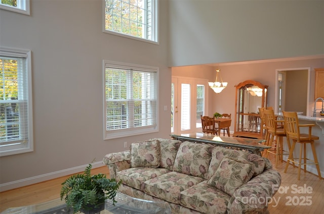 living room featuring a chandelier, a high ceiling, and light hardwood / wood-style floors