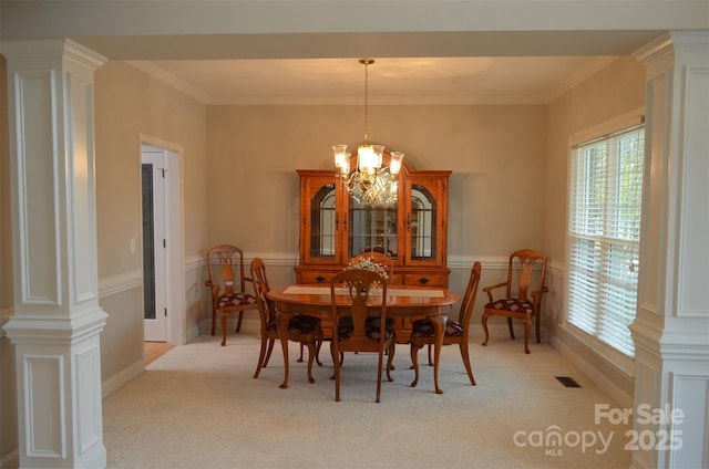 carpeted dining room with ornate columns, crown molding, and a chandelier