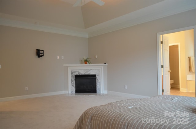 carpeted bedroom with ensuite bath, ceiling fan, a high end fireplace, crown molding, and lofted ceiling