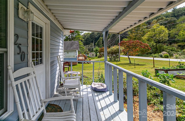 wooden deck featuring an outdoor structure and a lawn