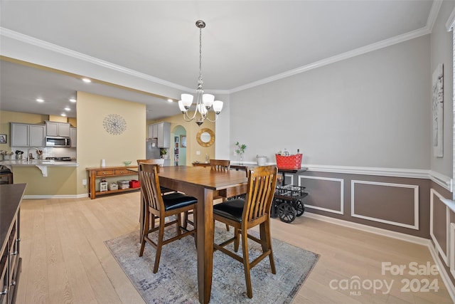 dining area featuring an inviting chandelier, light hardwood / wood-style flooring, sink, and crown molding