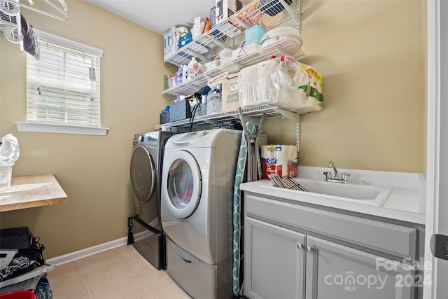 laundry area featuring sink, light tile patterned flooring, cabinets, and separate washer and dryer