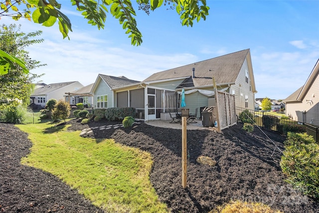 back of property featuring a patio, a lawn, and a sunroom