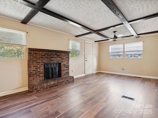 unfurnished living room with hardwood / wood-style floors, coffered ceiling, ceiling fan, a fireplace, and beamed ceiling