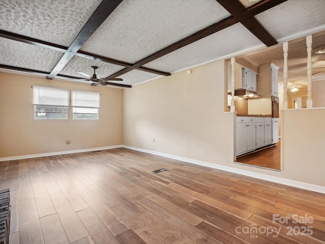 spare room with hardwood / wood-style floors, coffered ceiling, ceiling fan, a textured ceiling, and beam ceiling