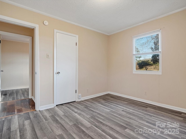 spare room with wood-type flooring, a textured ceiling, and ornamental molding