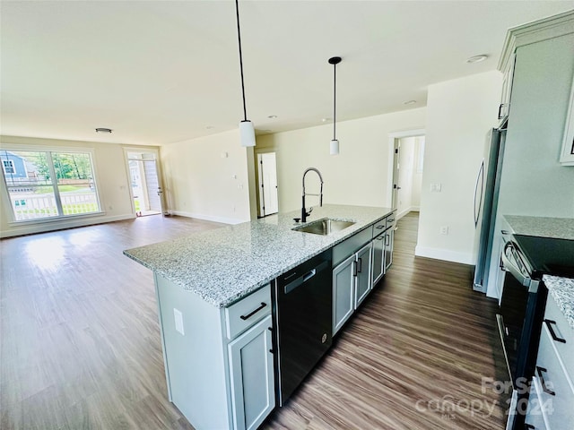 kitchen featuring light stone counters, appliances with stainless steel finishes, dark wood-type flooring, sink, and decorative light fixtures