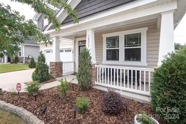 view of exterior entry featuring a garage and covered porch