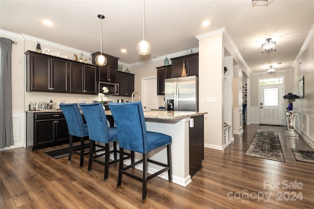 kitchen featuring decorative light fixtures, an island with sink, appliances with stainless steel finishes, and ornamental molding