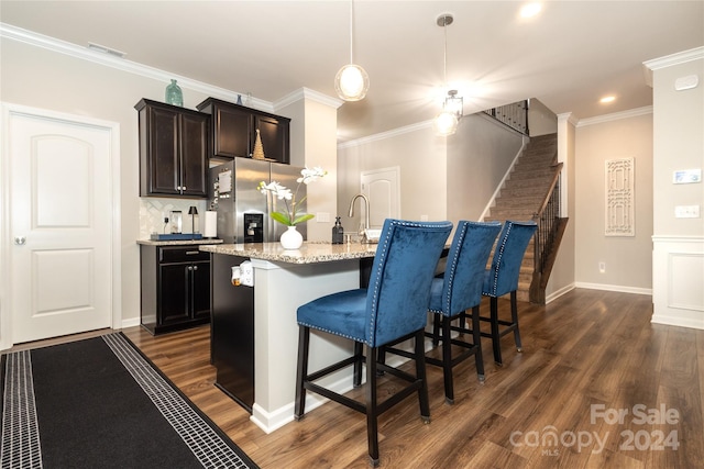 kitchen with a breakfast bar area, a center island with sink, dark wood-type flooring, and stainless steel fridge with ice dispenser