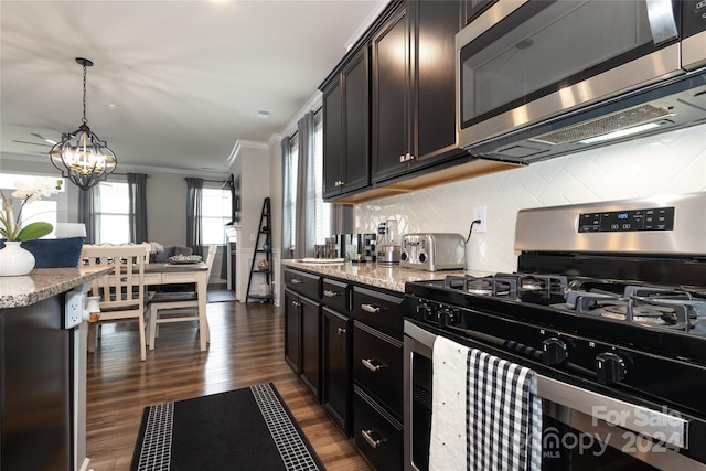 kitchen featuring appliances with stainless steel finishes, hanging light fixtures, dark hardwood / wood-style flooring, light stone countertops, and crown molding