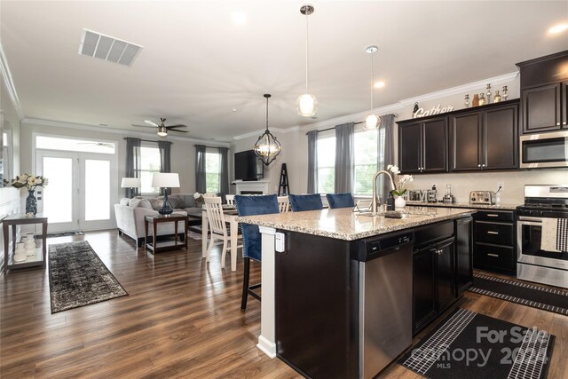 kitchen featuring appliances with stainless steel finishes, a breakfast bar area, ceiling fan, a center island with sink, and sink