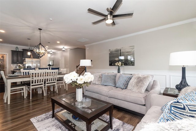 living room featuring ornamental molding, ceiling fan with notable chandelier, and dark hardwood / wood-style flooring