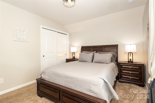 carpeted bedroom featuring vaulted ceiling and a closet