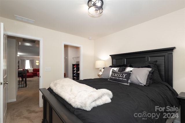 bedroom with light carpet and a walk in closet