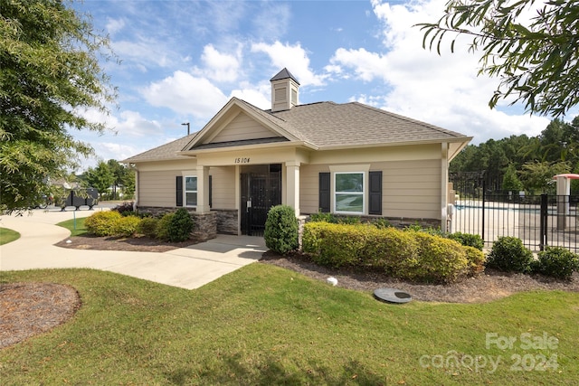 view of front of home with a fenced in pool and a front lawn