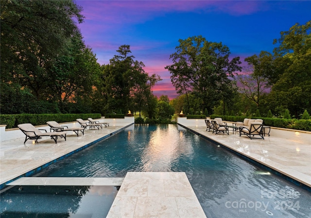 pool at dusk with a patio area