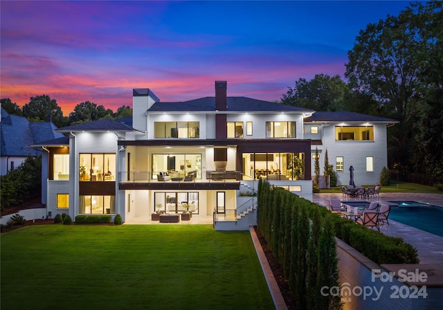 back house at dusk featuring an outdoor hangout area, a yard, a balcony, and a patio area