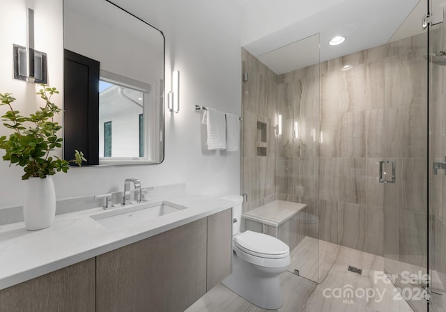 bathroom with vanity, toilet, and a shower with shower door