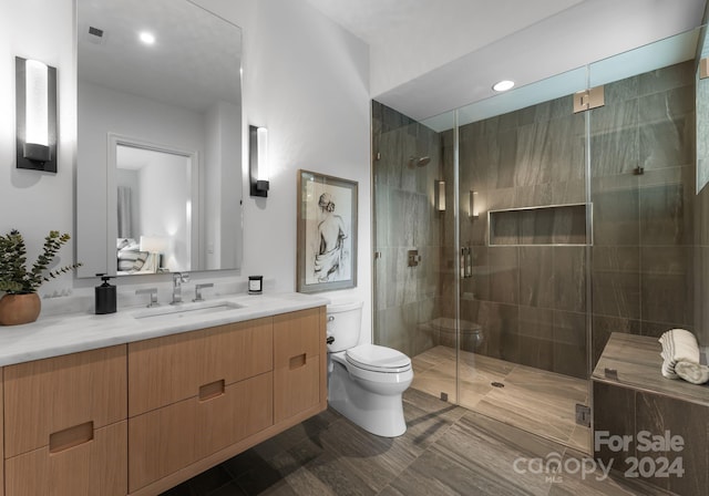 bathroom with vanity, toilet, and a shower with door