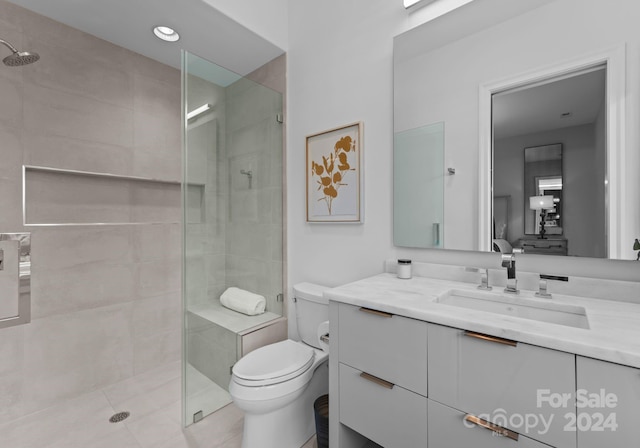 bathroom with vanity, tile patterned flooring, toilet, and tiled shower