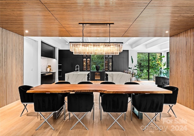 dining room featuring wooden walls, an inviting chandelier, and light hardwood / wood-style flooring