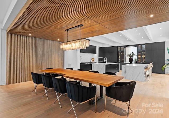 bar featuring light hardwood / wood-style flooring, wooden walls, beam ceiling, and decorative light fixtures