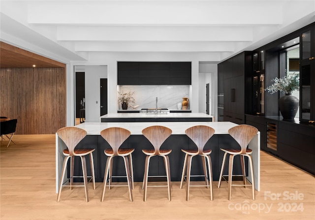 kitchen featuring light wood-type flooring, a center island, beamed ceiling, and tasteful backsplash