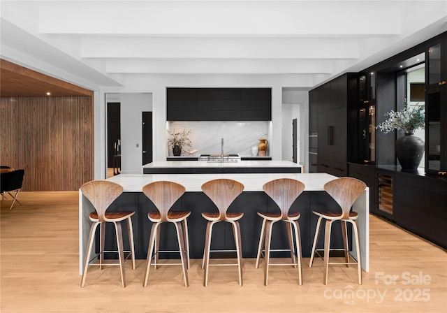 2116 Woodhaven Rd, Charlotte, NC 28211 - kitchen featuring light countertops, decorative backsplash, light wood-style floors, modern cabinets, and dark cabinets