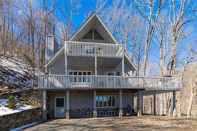 rear view of property featuring a chimney and a balcony