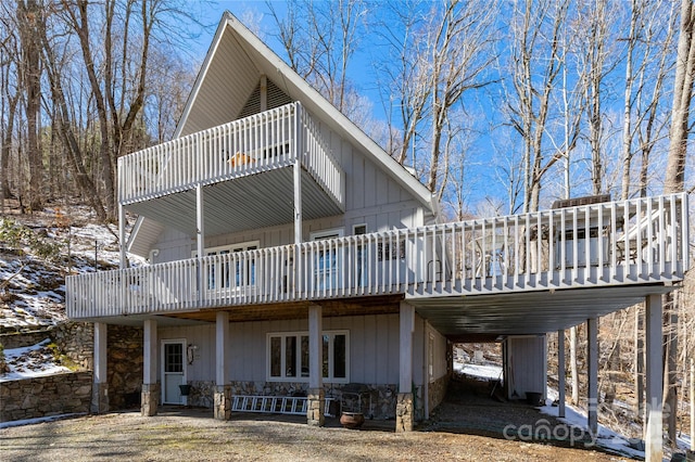 rear view of house featuring an attached carport, board and batten siding, and a wooden deck