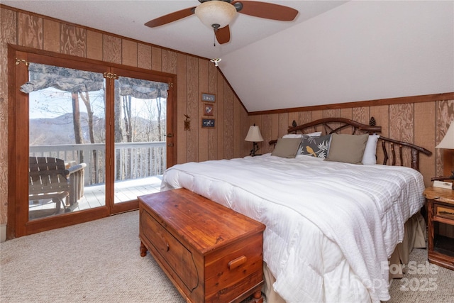 bedroom with wooden walls, light carpet, a ceiling fan, access to exterior, and vaulted ceiling