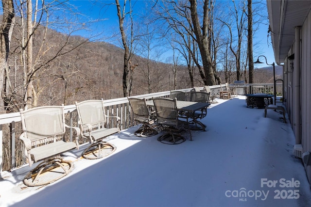 deck featuring outdoor dining area and a wooded view