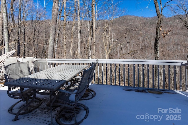 deck with outdoor dining area and a view of trees