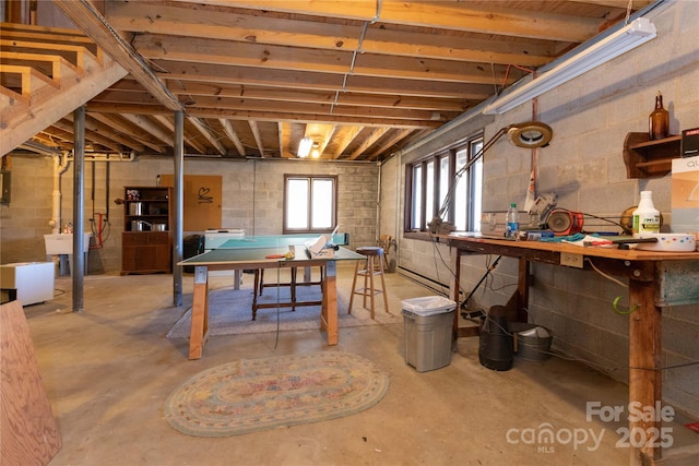 below grade area with concrete block wall, washer / clothes dryer, a sink, and a workshop area