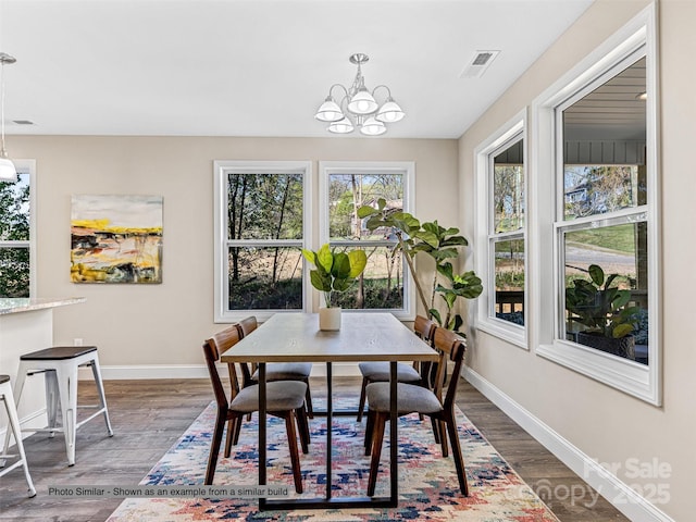 dining space with hardwood / wood-style floors and an inviting chandelier