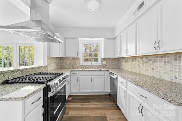 kitchen with white cabinetry, wall chimney range hood, stainless steel appliances, and a wealth of natural light