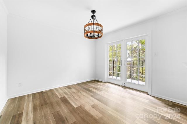 unfurnished room with light wood-type flooring, crown molding, and a chandelier