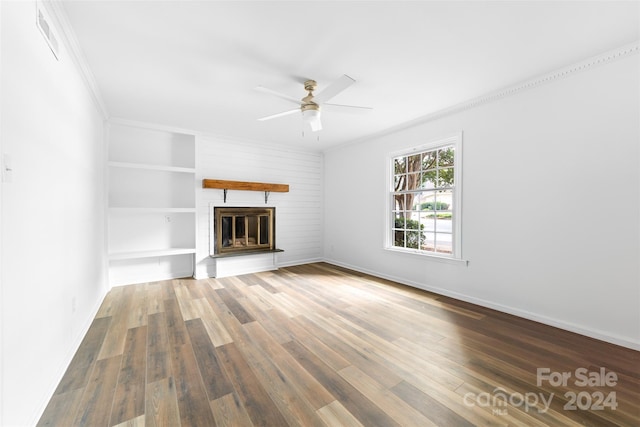 unfurnished living room with ornamental molding, dark hardwood / wood-style floors, ceiling fan, and a large fireplace