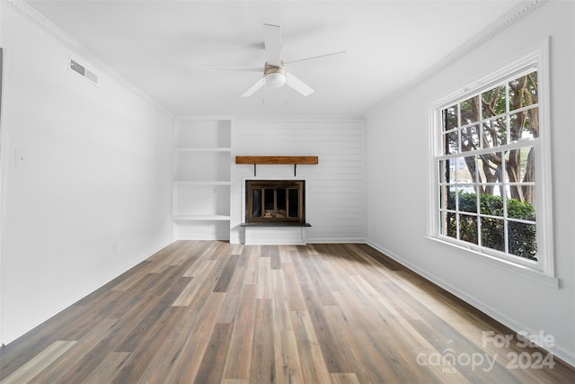 unfurnished living room featuring wood-type flooring, ceiling fan, a fireplace, and a healthy amount of sunlight