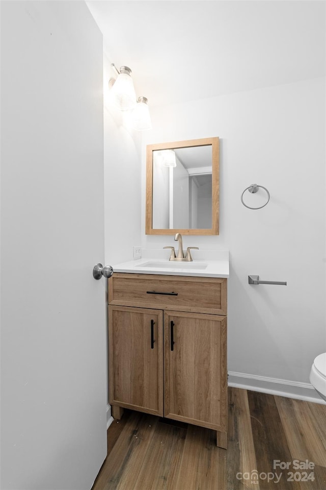 bathroom with wood-type flooring, vanity, and toilet