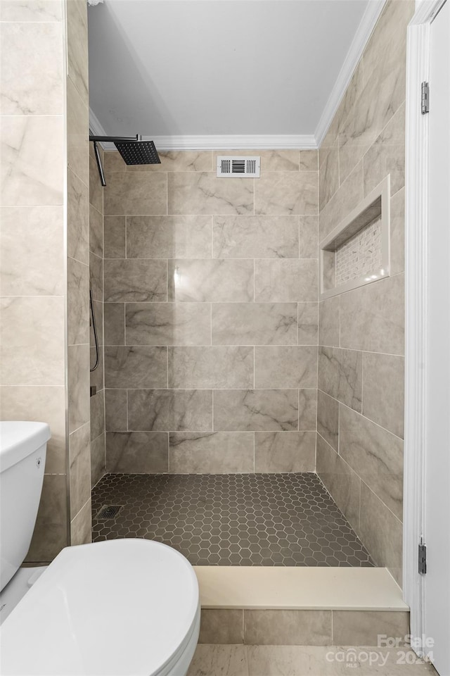 bathroom featuring tiled shower, ornamental molding, and toilet