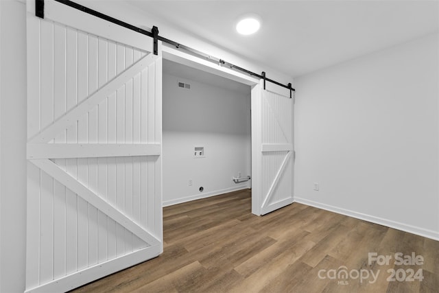 interior space with hookup for a washing machine, a barn door, and wood-type flooring